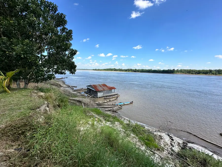 A river bank in the Peruvian Amazon with wooden canoes and a floating house
